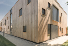 Holzfassade eines Kindergartens mit quadratischen Fenstern in unterschiedlichen Größen 